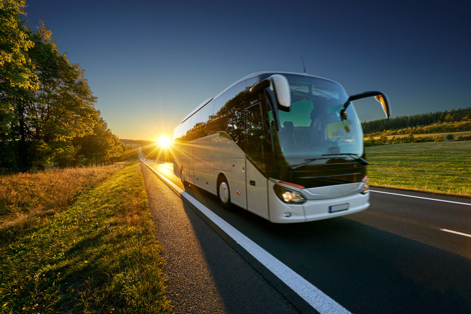 Bus Sales - Bus driving down the road as the sun sets in the background