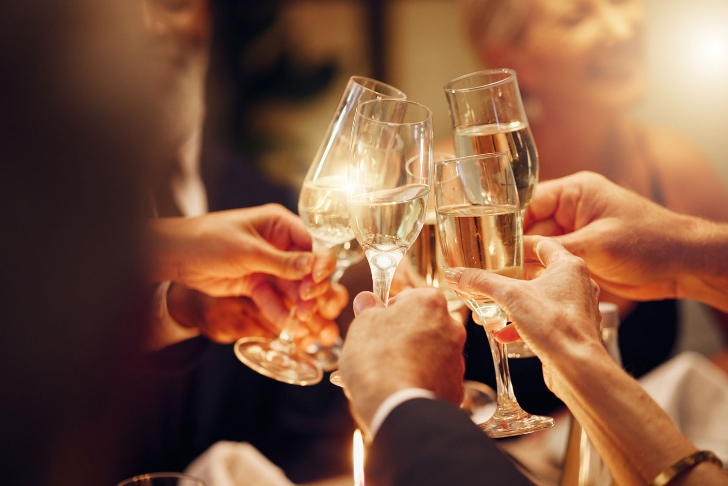 Banquests & Catering - Group of well dressed individuals joining together glasses of white wine to cheers the moment